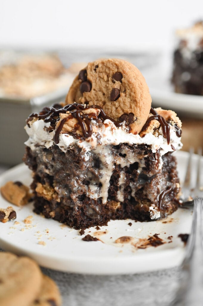 A piece of chocolate chip cookie poke cake with a forkful taken out of it.