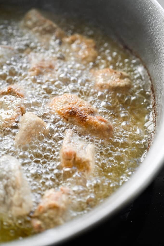 Pork bites being fried in a little bit of oil.