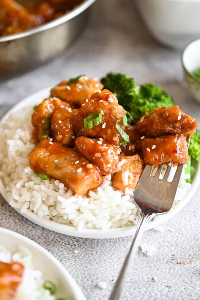 A white plate with rice, sticky pork, and steamed broccoli.