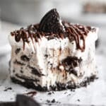 A slice of Oreo ice cream cake on a white plate.