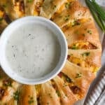 A breakfast crescent ring with a bowl of white gravy in the middle.