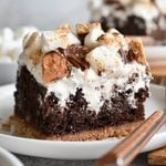 A piece of S'mores Poke Cake on a white plate.