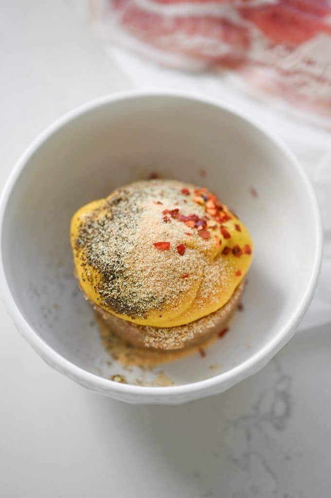 Brown sugar, mustard, and seasonings in a small white bowl.
