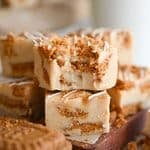 Two pieces of Biscoff fudge stacked; the top one has a bite out of it.